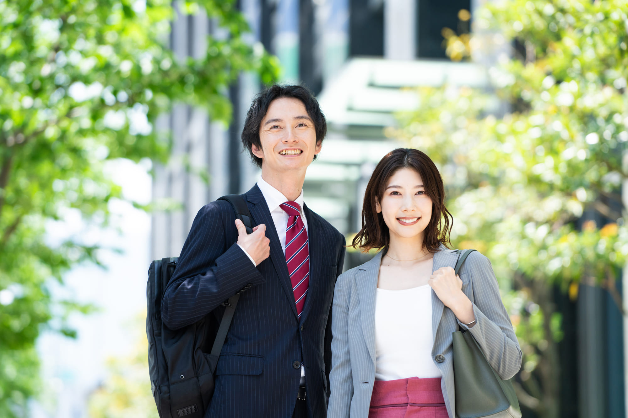 新緑のオフィス街に立つビジネスパーソン